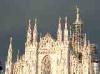 Mailand: The Duomo with dark clouds behind and illuminated by the sunset sun